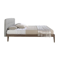 Letto Luxor con design minimalista, testiera capitonné grigia e struttura in legno noce, vista laterale.