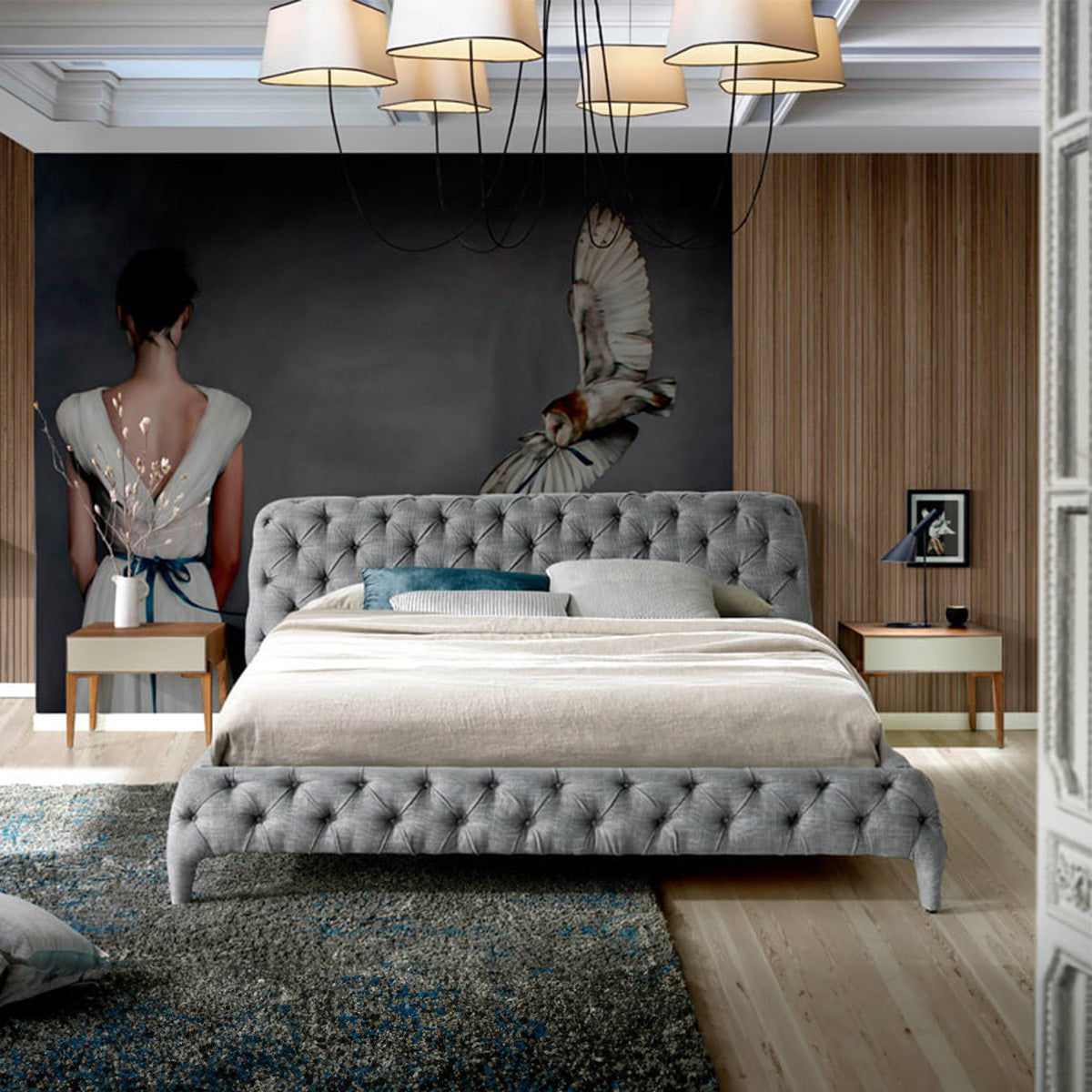 Letto Marene matrimoniale in una camera moderna con pareti in legno, rivestimento grigio capitonné e comodini abbinati.