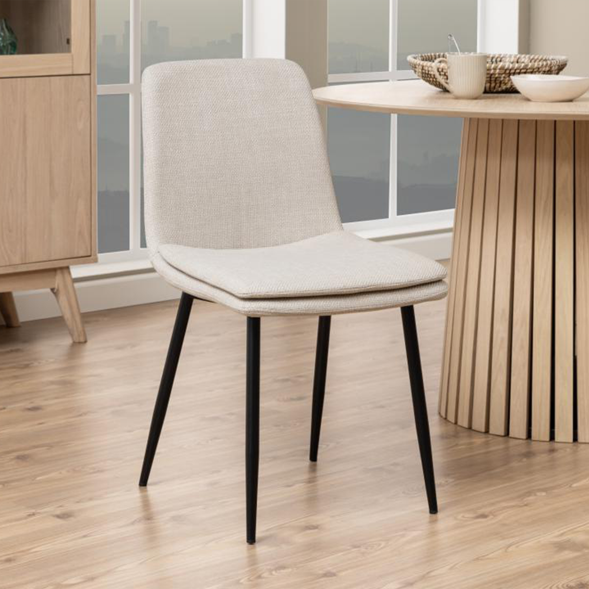Sedia Bella beige accanto a un tavolo in legno chiaro, perfetta per arredare sale da pranzo luminose e moderne.