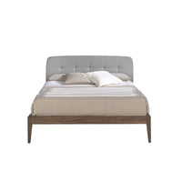 Vista frontale del Letto Luxor con testiera capitonné in tessuto grigio e struttura in legno noce.