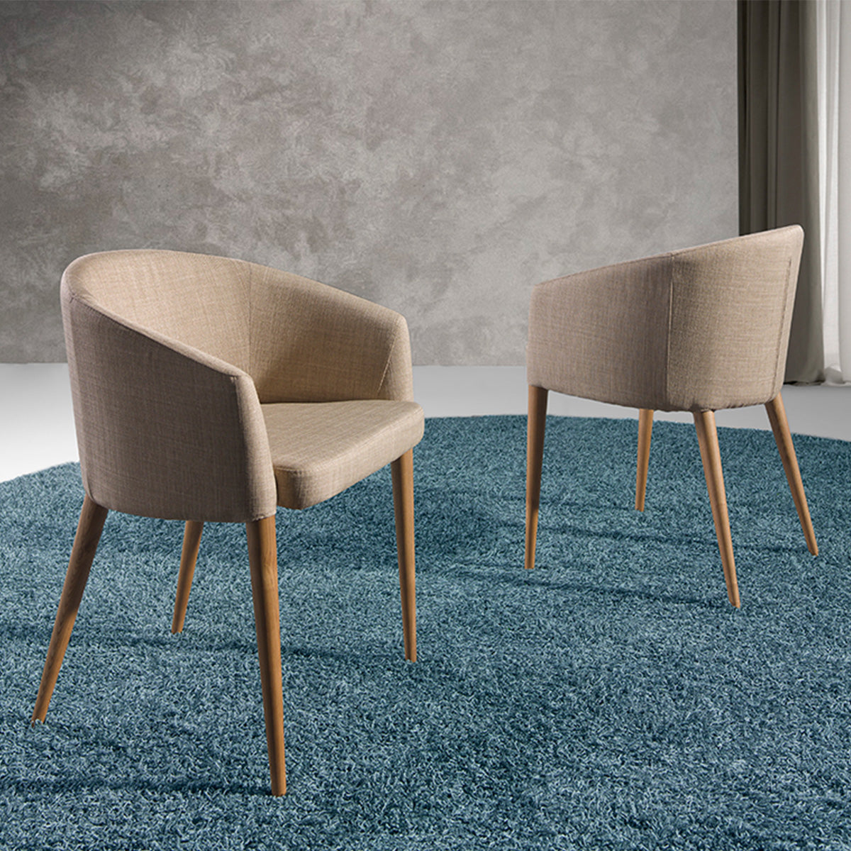 Due sedie Lowell in tessuto beige con gambe in legno su tappeto blu, perfette per ambienti moderni.
