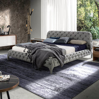 Letto Marene matrimoniale in una camera luminosa con rivestimento grigio capitonné e arredi moderni in legno.