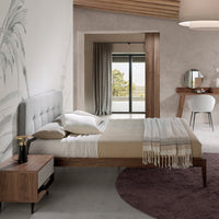 Letto Luxor in una camera da letto moderna con dettagli in legno noce e testiera capitonné grigia.