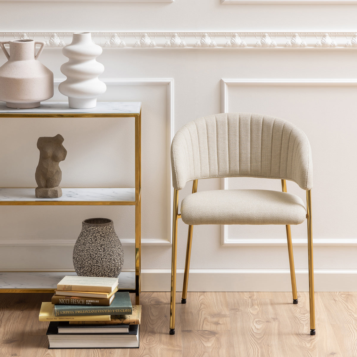 Sedia Brooke beige posizionata in un ambiente elegante con scaffale decorativo, ideale per interni moderni e raffinati.