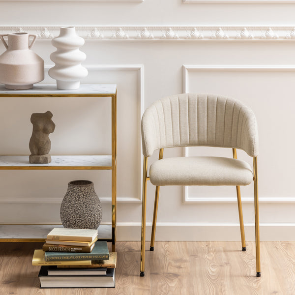 Sedia Brooke beige posizionata in un ambiente elegante con scaffale decorativo, ideale per interni moderni e raffinati.